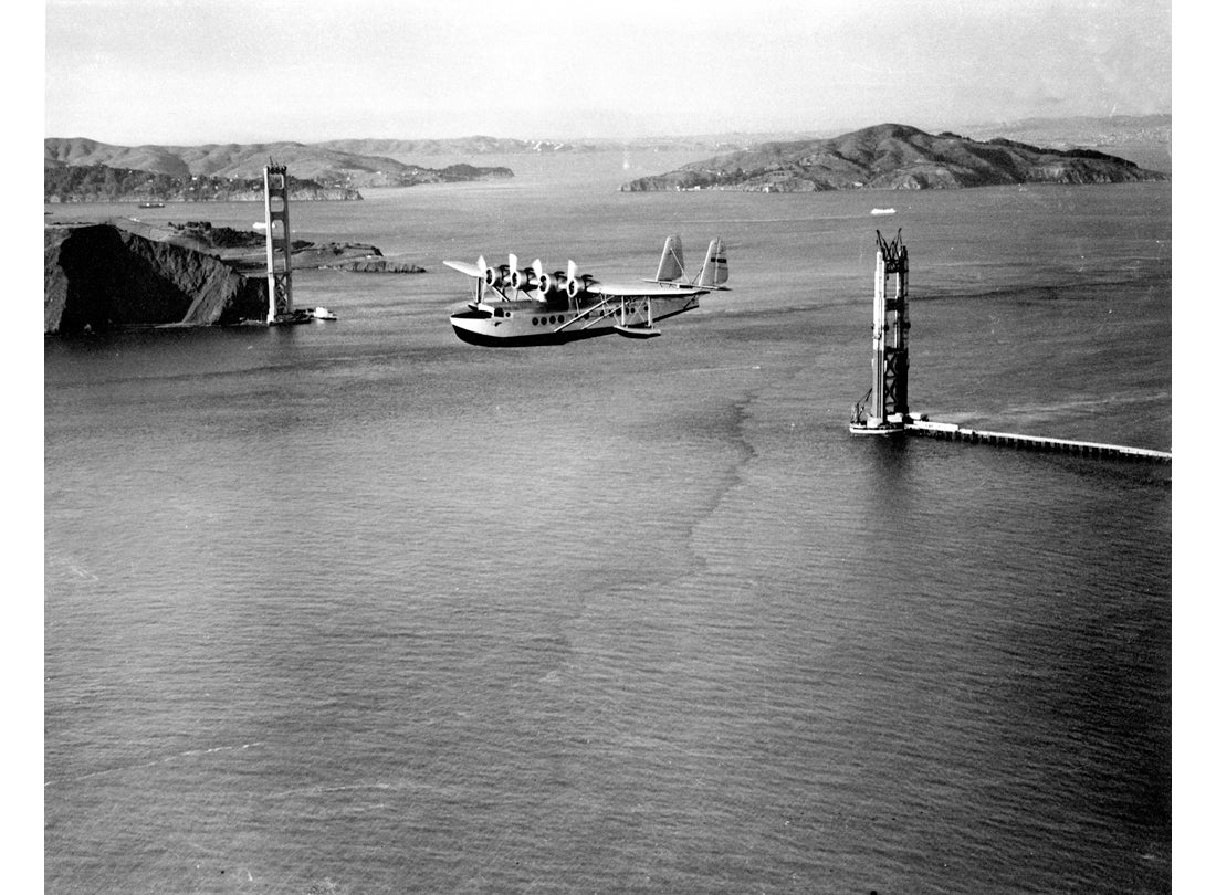 Sikorsky S-42 airplane flying over the Golden Gate Bridge before completion
