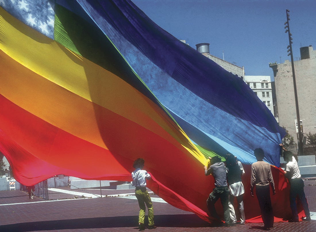 Gilbert Baker (in vest) and colleagues raising one of the first rainbow flags at United Nations Plaza in San Francisco