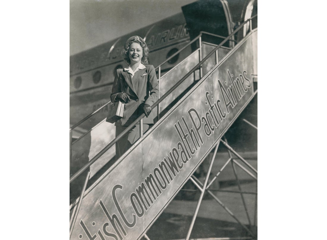 BCPA (British Commonwealth Pacific Airlines) stewardess Daughne Kelpe on the stairs next to a BCPA Douglas DC-4  late 1940s