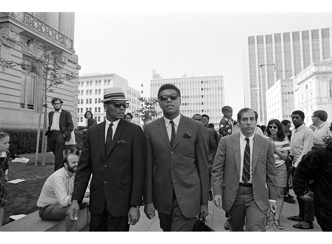 Muhammad Ali walking near San Francisco’s Civic Center with a Nation of Islam security guard on his right and sports journalist Robert Lipsyte—who covered Ali from 1964 until his death—on his left. Ali later spoke to thousands outside City Hall during a rally to protest war, racism, and poverty  April 27, 1968 
