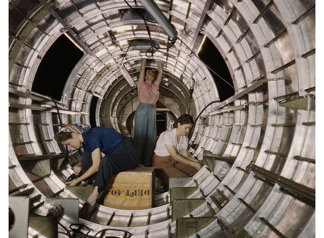 Workers install fixtures and assemblies to a tail fuselage section of a Douglas-built Boeing B-17F