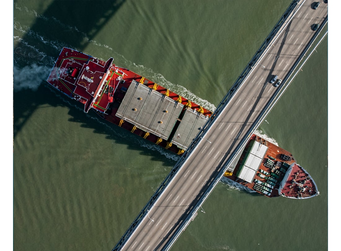 Ship loaded with steel-deck sections passes under Bay Bridge