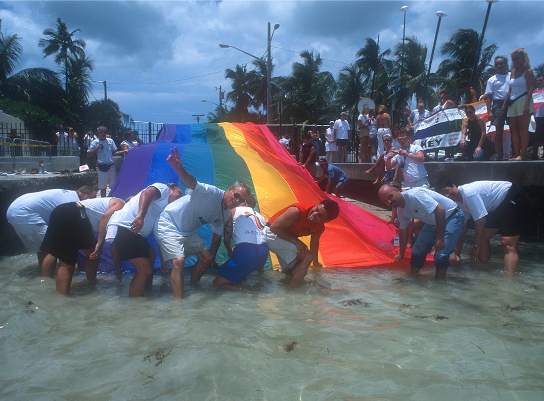 LGBTQ activist and labor organizer Cleve Jones (with hand raised) and colleagues with the 1.25 mile-long “Sea-to-Sea” flag created by Gilbert Baker and a team of volunteers. The flag was produced for the 25th Anniversary of the rainbow flag and unfurled from the Gulf of Mexico to the Atlantic Ocean on Duval Street in Key West, Florida