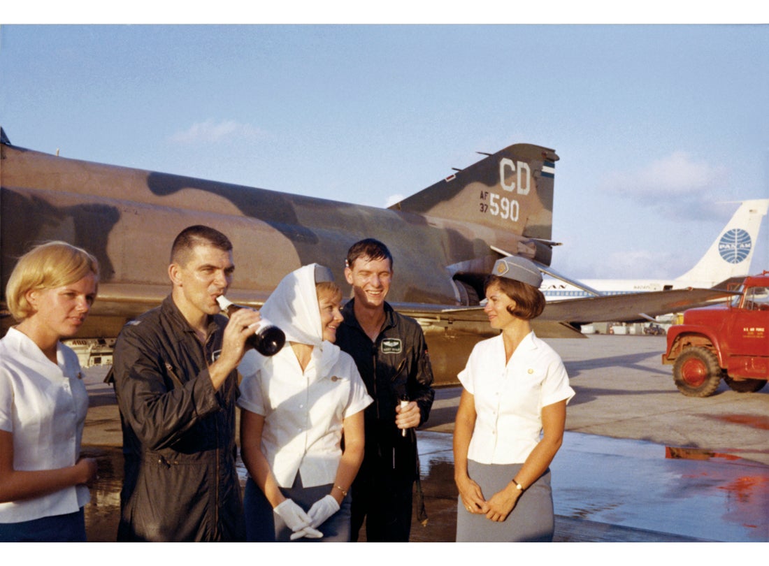 Flight attendant Mary Jo Hunt (left) and Pan American World Airways crew with fighter pilots, Da Nang Air Base, Vietnam  c. 1968