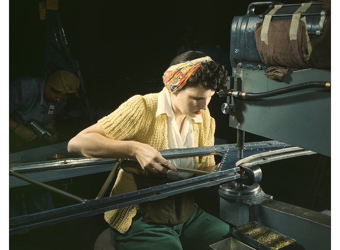 An operator of a riveting machine joins sections of wing ribs to reinforce the inner wing assemblies of Douglas-built Boeing B-17F