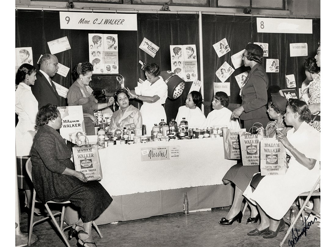 Hair demonstration in the Madam C. J. Walker booth at the Regional Beauty College Convention; Walker’s attorney F. B. Ransom, who played a significant role in her business and personal life, is pictured on the left