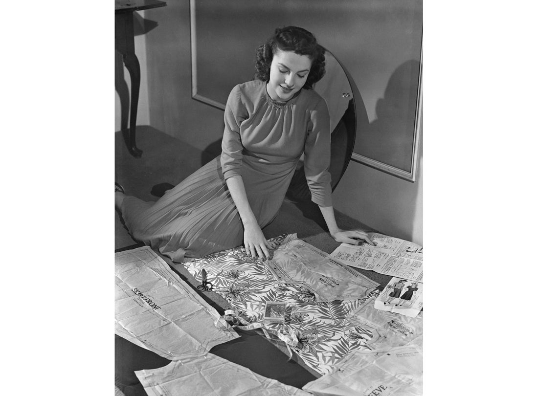 A woman demonstrates the steps in assembling a pattern and fabricating a garment at home for the Office of War Information  1943