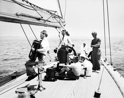 Ranger’s afterguard in a relaxed moment: Owner/Skipper Harold Vanderbilt at the wheel; Navigator Zena Bliss and Mrs. Gertrude Vanderbilt seated; rigging specialist Rod Stephens with accordion; and Ranger’s co-designer Olin Stephens with arms crossed  1937