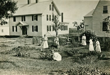 Shaker girls working in the garden near the ministry shop and meeting house