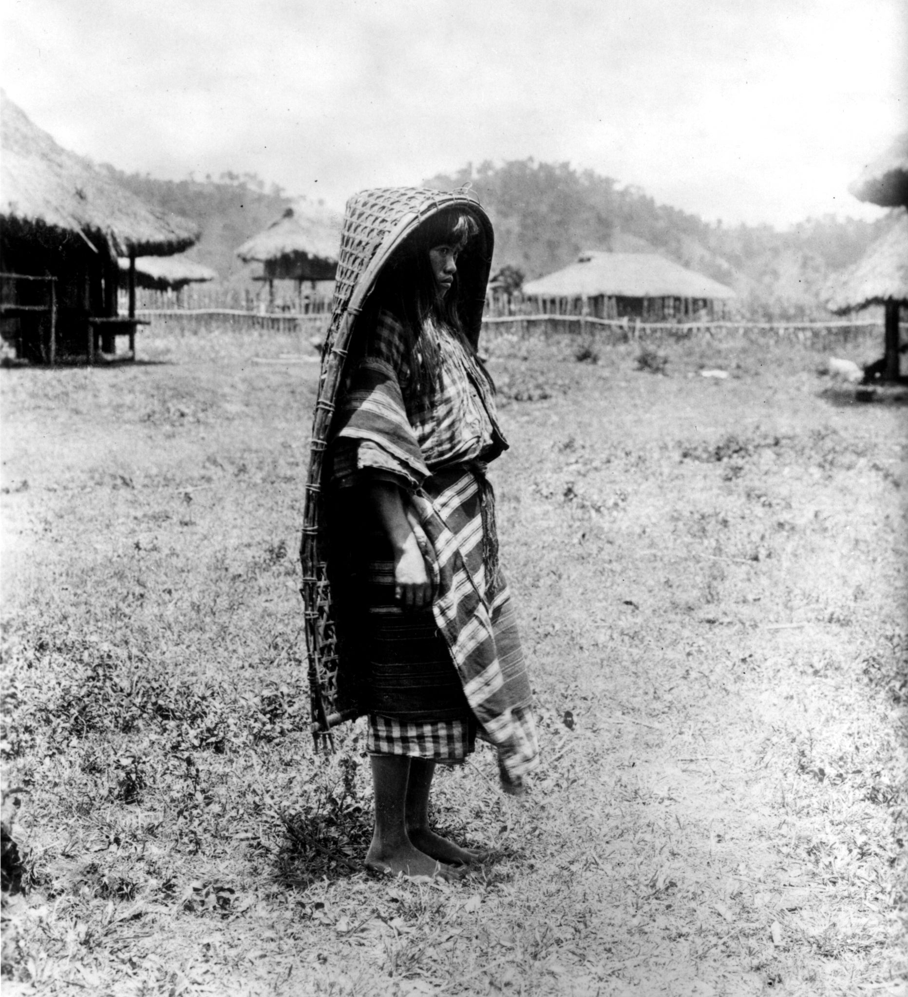 An Ibaloi woman models the way in which a carrying basket can be used as a rain cape early 1900s; Fowler Museum at UCLA, Day Collection; R2013.0801.061
