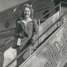 BCPA (British Commonwealth Pacific Airlines) stewardess Daughne Kelpe on the stairs next to a BCPA Douglas DC-4  late 1940s