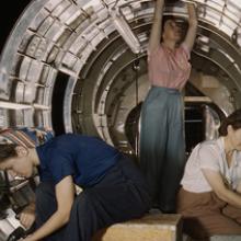 Workers install fixtures and assemblies to a tail fuselage section of a Douglas-built Boeing B-17F