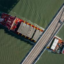 Ship loaded with steel-deck sections passes under Bay Bridge