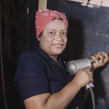 A worker operates a hand drill while working on the horizontal stabilizer of a Vultee A-31 Vengeance dive bomber at the Vultee Aircraft plant
