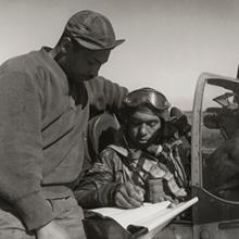 Crew chief Marcellus G. Smith with pilot Woodrow W. Crockett of the 332nd Fighter Group signing the Form One Book, indicating any discrepancies of aircraft prior to takeoff  March 1945
