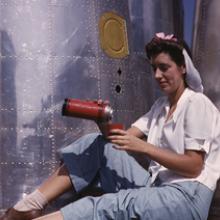 A worker during her lunch break with heavy bomber nacelle parts in the background at the Douglas Aircraft Company plant